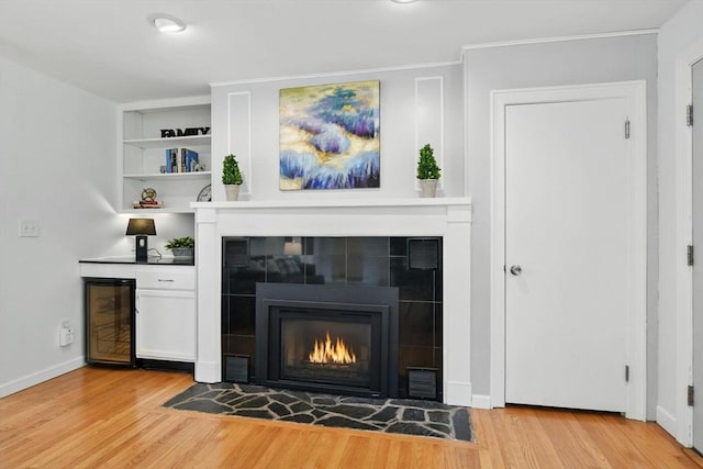 9 E Colonial Rd, Wilbraham, MA 01095 - living room with light wood-style flooring, wine cooler, a tile fireplace, crown molding, and a bar
