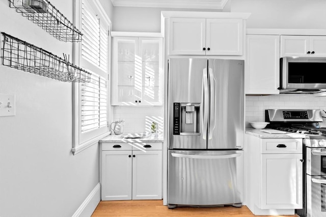 kitchen with ornamental molding, appliances with stainless steel finishes, backsplash, and white cabinets