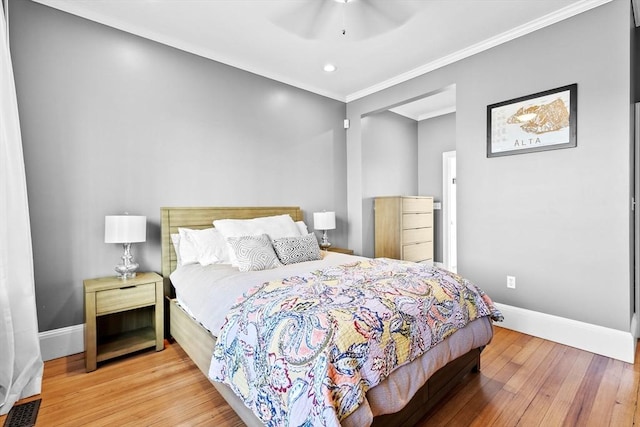 bedroom featuring ornamental molding, visible vents, baseboards, and wood finished floors