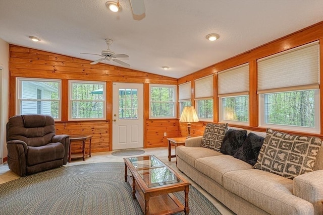 living room with ceiling fan, vaulted ceiling, wood walls, and carpet