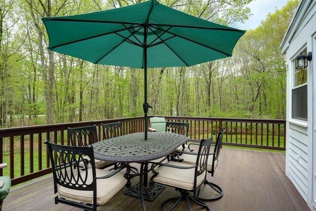 wooden deck featuring outdoor dining space and a wooded view