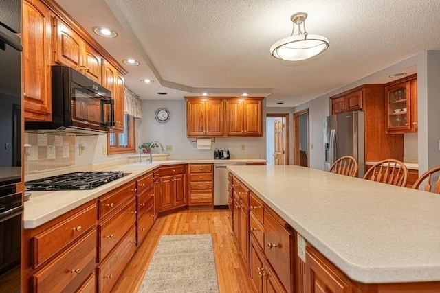 kitchen with stainless steel appliances, light wood-style floors, recessed lighting, a kitchen island, and glass insert cabinets