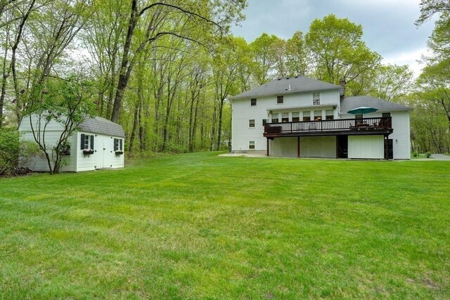 view of grassy yard featuring a deck, an outbuilding, and a storage shed