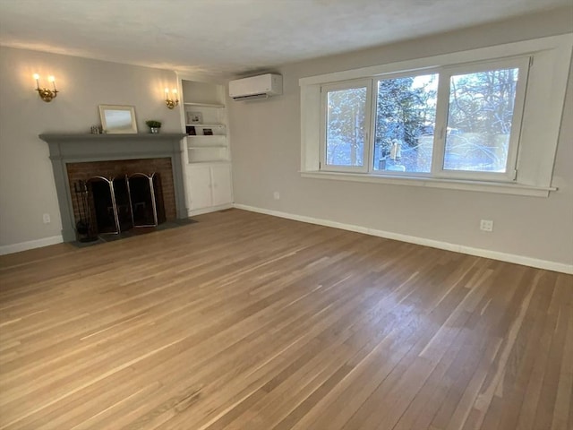 unfurnished living room featuring an AC wall unit, hardwood / wood-style floors, and a brick fireplace