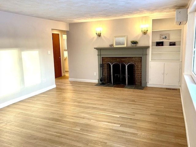 unfurnished living room featuring a fireplace, light hardwood / wood-style flooring, and a wall mounted AC