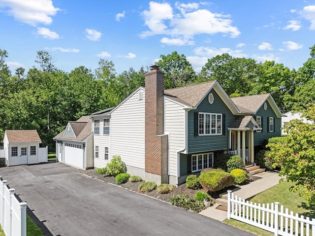 77 Columbus Dr, Fall River, MA 02720 - bi-level home with an outbuilding, a garage, a chimney, roof with shingles, and asphalt driveway