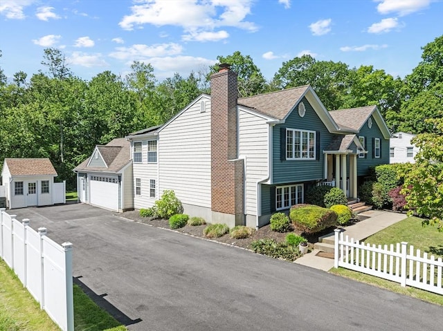 77 Columbus Dr, Fall River, MA 02720 - bi-level home featuring an outbuilding, a chimney, asphalt driveway, a shingled roof, and a garage