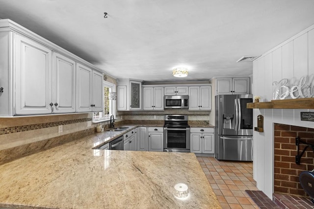 77 Columbus Dr, Fall River, MA 02720 - kitchen with stainless steel appliances, a sink, light tile patterned flooring, light stone counters, and a peninsula