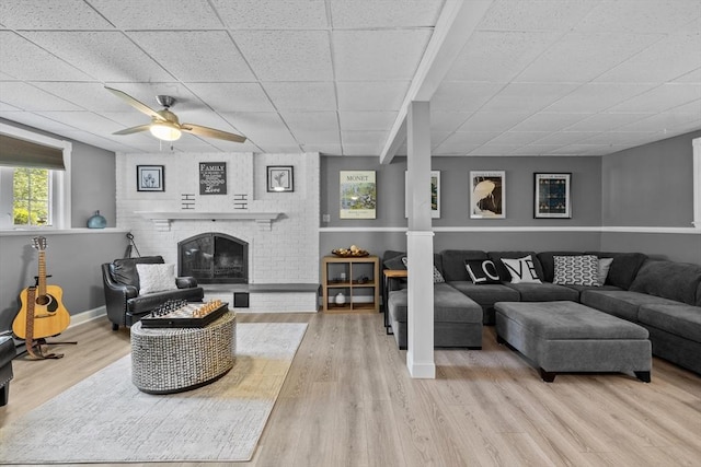 77 Columbus Dr, Fall River, MA 02720 - living room featuring a drop ceiling, a ceiling fan, wood finished floors, a brick fireplace, and baseboards