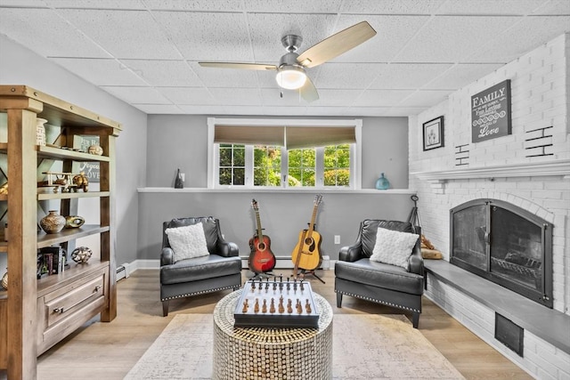 77 Columbus Dr, Fall River, MA 02720 - living area featuring a paneled ceiling, a ceiling fan, wood finished floors, a fireplace, and baseboard heating