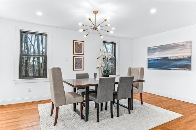 dining space with a chandelier, light wood finished floors, and baseboards