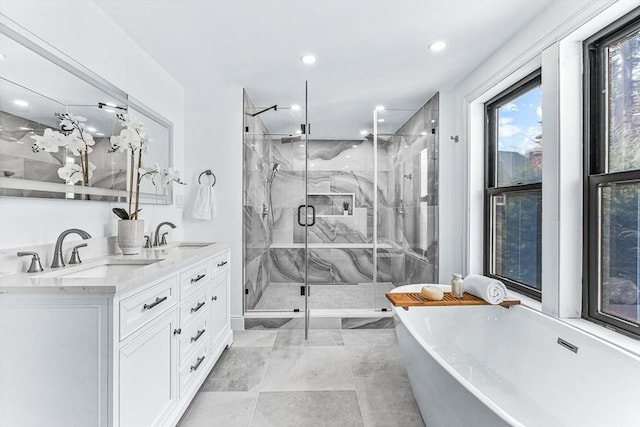 full bathroom featuring a freestanding bath, double vanity, a sink, and a marble finish shower