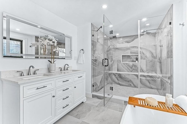 full bath featuring a freestanding tub, a sink, a marble finish shower, and double vanity