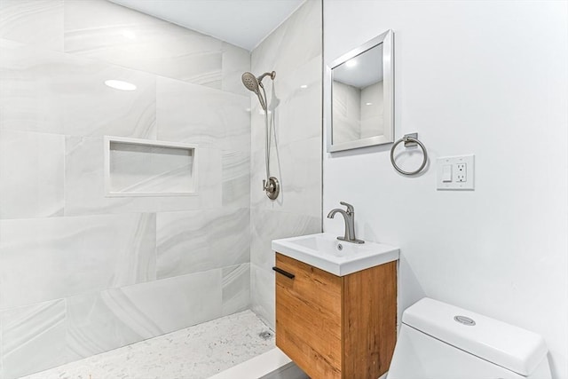 full bath featuring toilet, tiled shower, and vanity