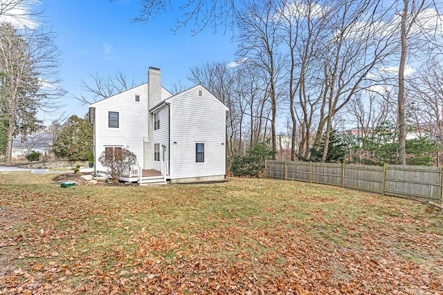 view of property exterior featuring a yard, fence, a chimney, and a deck