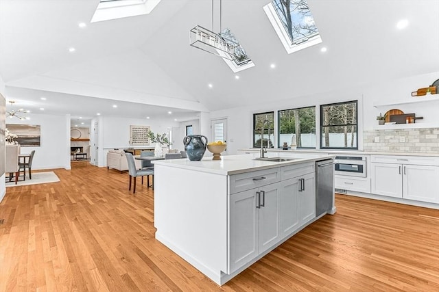 kitchen with a skylight, light countertops, a sink, and light wood finished floors