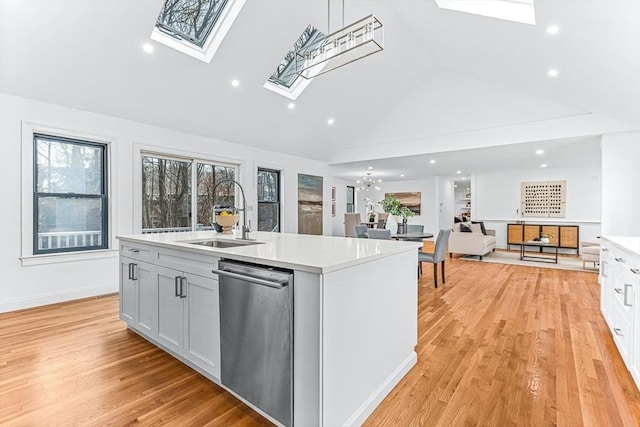 kitchen with light countertops, stainless steel dishwasher, a skylight, and a sink