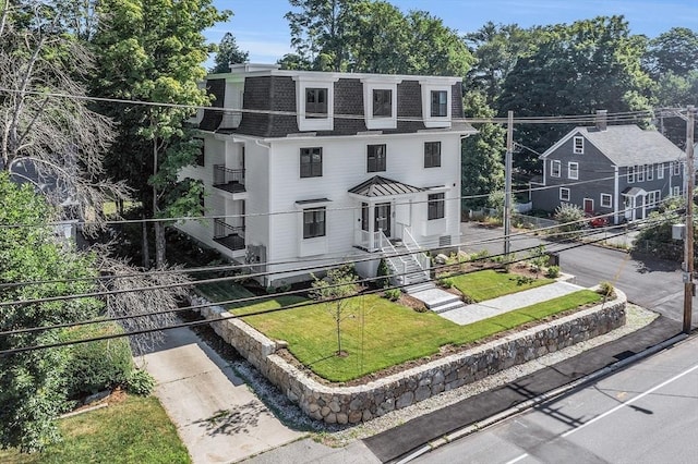 second empire-style home featuring a shingled roof, a front lawn, and mansard roof
