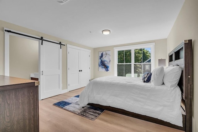bedroom with light wood-style flooring and a barn door