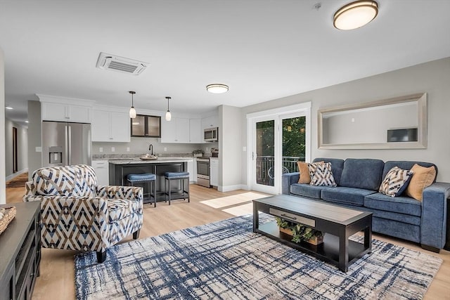living area featuring baseboards, visible vents, and light wood-style floors