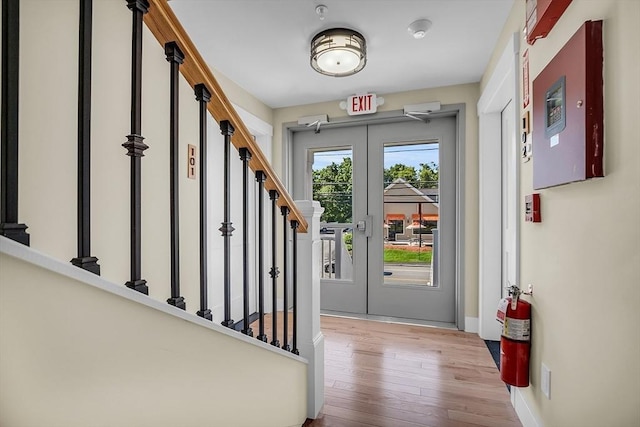 interior space with baseboards, wood-type flooring, french doors, and stairs
