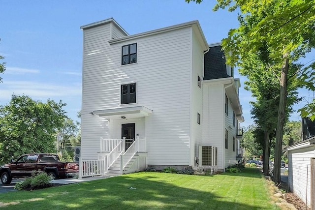 rear view of house featuring a lawn and cooling unit