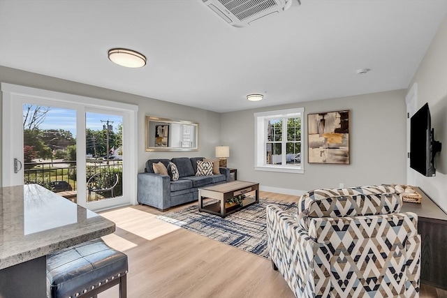 living room featuring visible vents, a wealth of natural light, and light wood-type flooring