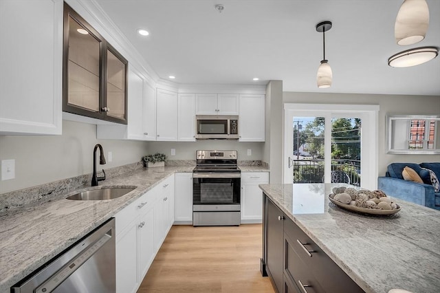 kitchen featuring a sink, appliances with stainless steel finishes, pendant lighting, and white cabinetry