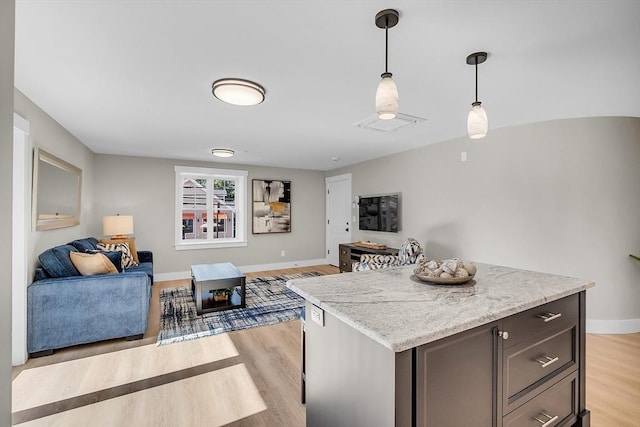 kitchen featuring light wood-style flooring, baseboards, open floor plan, decorative light fixtures, and a kitchen island