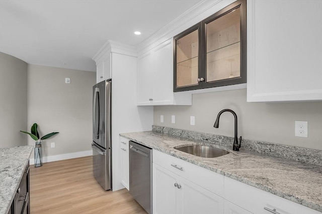 kitchen featuring glass insert cabinets, light wood-type flooring, white cabinetry, a sink, and stainless steel appliances