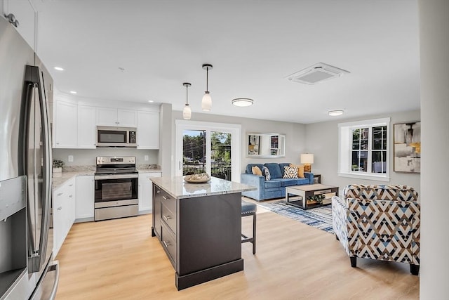 kitchen with light stone countertops, stainless steel appliances, light wood-type flooring, and white cabinetry