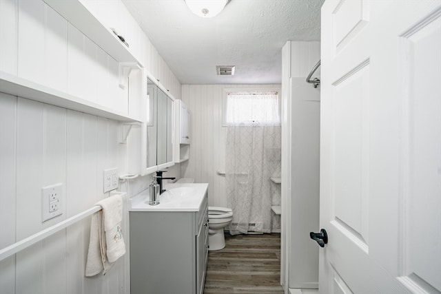 bathroom featuring walk in shower, wood-type flooring, a textured ceiling, toilet, and vanity