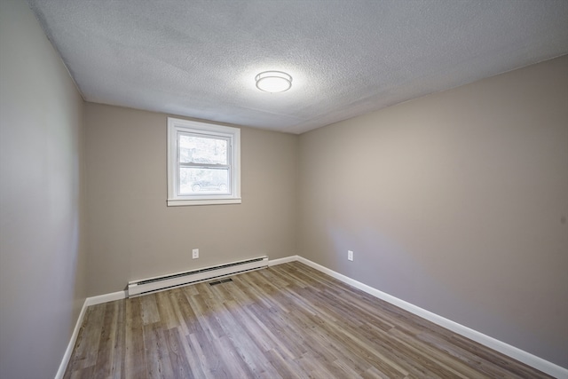 empty room featuring a baseboard radiator, light wood-type flooring, and a textured ceiling