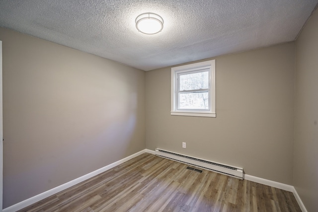 unfurnished room featuring a baseboard heating unit, a textured ceiling, and hardwood / wood-style flooring