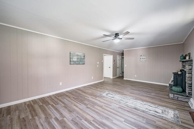 unfurnished living room featuring wood-type flooring, crown molding, ceiling fan, and wooden walls