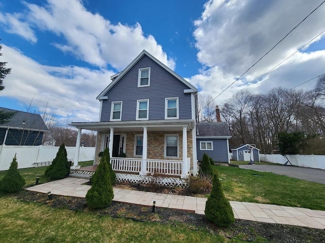 6 Pond St, Avon, MA 02322 - traditional home featuring stone siding, covered porch, fence, an outbuilding, and a front lawn