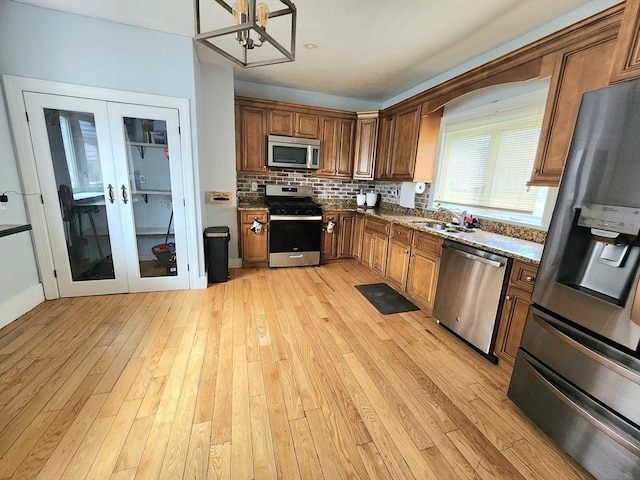 6 Pond St, Avon, MA 02322 - kitchen featuring light wood-type flooring, a sink, stainless steel appliances, french doors, and decorative backsplash