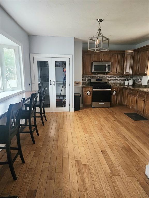 6 Pond St, Avon, MA 02322 - kitchen with stainless steel appliances, light wood-style flooring, french doors, and decorative backsplash
