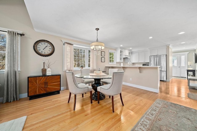 dining room featuring an inviting chandelier, light hardwood / wood-style flooring, and ornamental molding