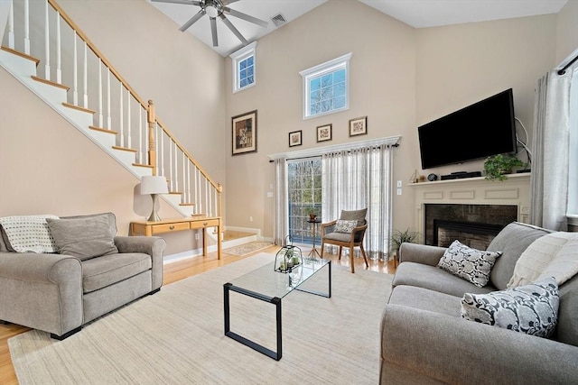 living room with hardwood / wood-style flooring, ceiling fan, and a high ceiling