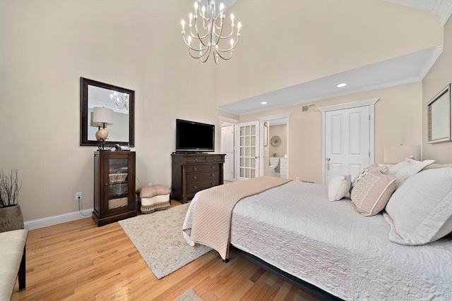 bedroom with a high ceiling, ornamental molding, a chandelier, and light hardwood / wood-style floors