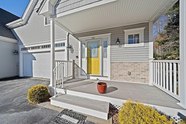 view of exterior entry with a garage and a porch