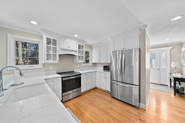 kitchen with sink, stainless steel appliances, white cabinets, and light wood-type flooring