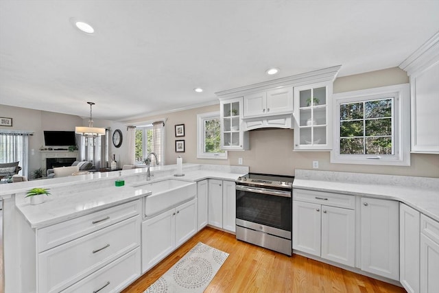 kitchen with sink, white cabinets, stainless steel range with electric cooktop, custom exhaust hood, and light hardwood / wood-style floors