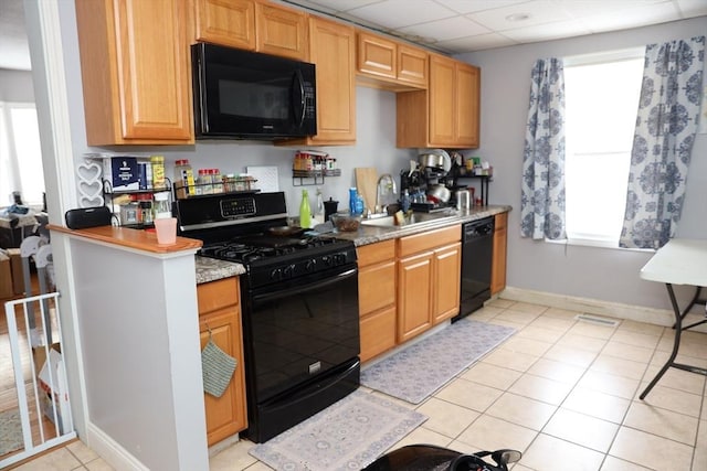 kitchen featuring sink, a paneled ceiling, light tile patterned floors, and black appliances