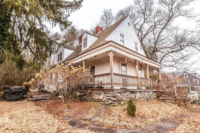 country-style home with covered porch and a chimney