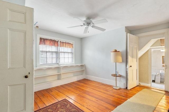 sitting room featuring wood-type flooring, baseboards, and a ceiling fan