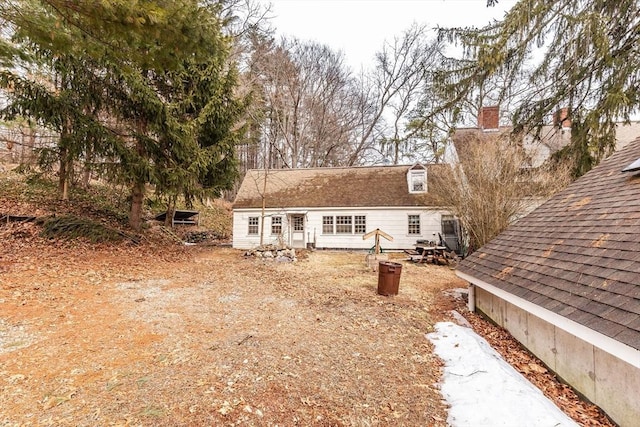 rear view of property with a shingled roof and a chimney