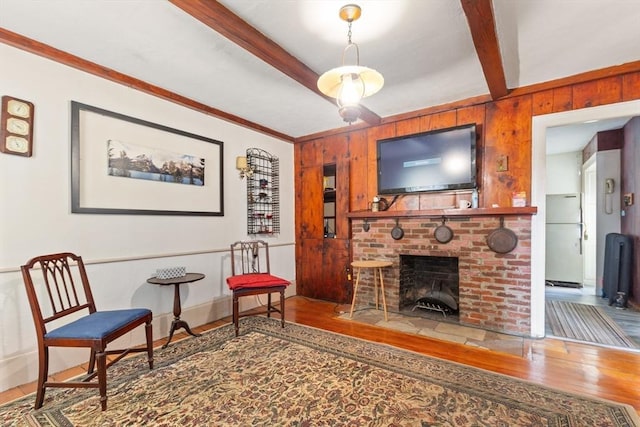 living area featuring ornamental molding, a brick fireplace, wood walls, and wood finished floors