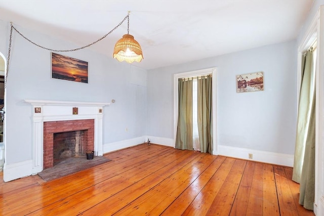 unfurnished living room with light wood-type flooring, a fireplace, and baseboards